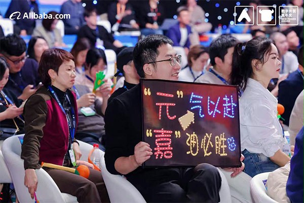 上图为：后援团举出“元气以赴，嘉油必胜”的牌子为杨元嘉加油鼓劲